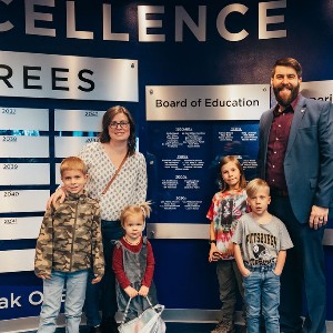 Aaron Salt and his family in front of the Hall of Excellence wall