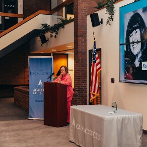 Kathie Crume's photo on the screen, while her award is accepted by a friend on her behalf