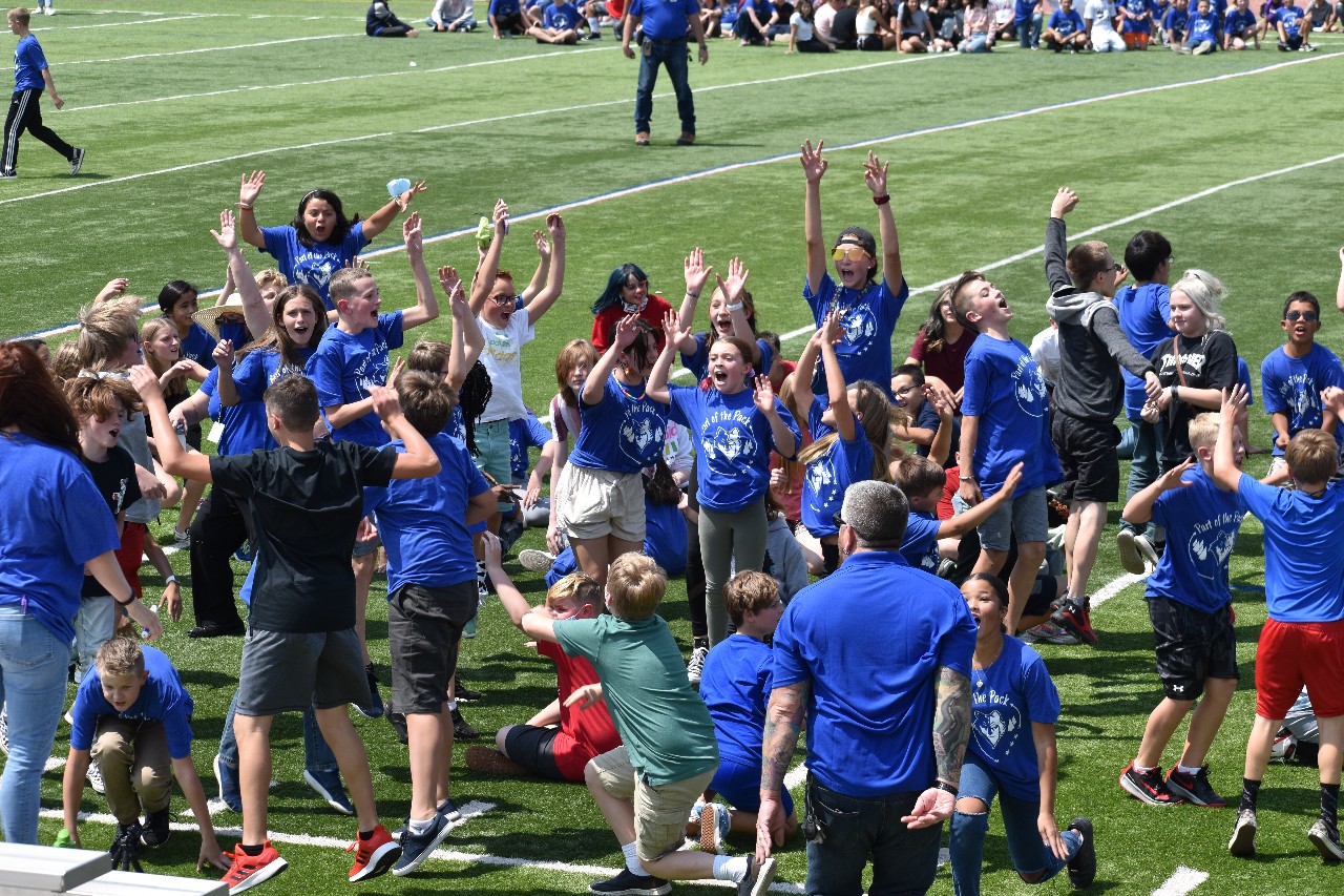 TMS students cheer on the field during an athletics event.