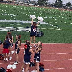 Lancer Cheerleaders assist young student in a cheerleading stunt during a Liberty Football game.