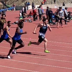 Boys running with batons during relay race.