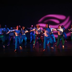 Dancers perform on Liberty's stage in front of purple lights. 
