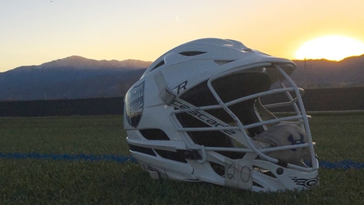 A Lacrosse helmet sitting on the playing field.