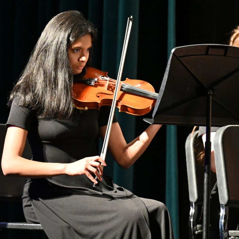 Student playing violin from music on a stand