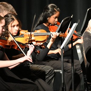 three students playing violin