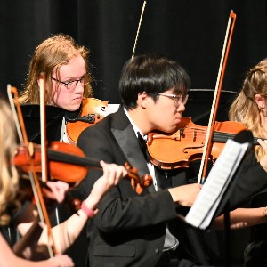 Two male students playing violin in concert