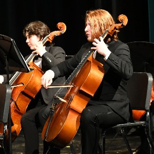 Two students playing cello in concert