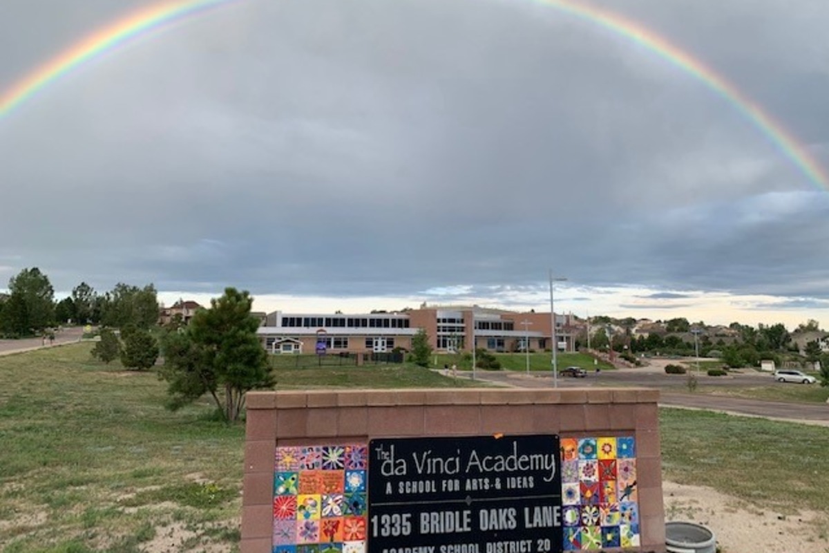 The da Vinci Academy sign in front of the school with a rainbow overhead.
