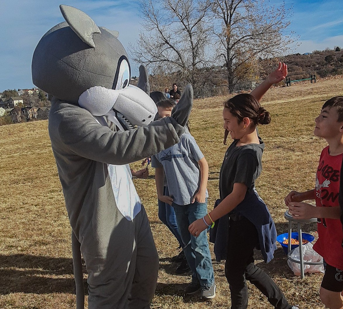 Our Mascot Timber, a wolf, high-fiving a student