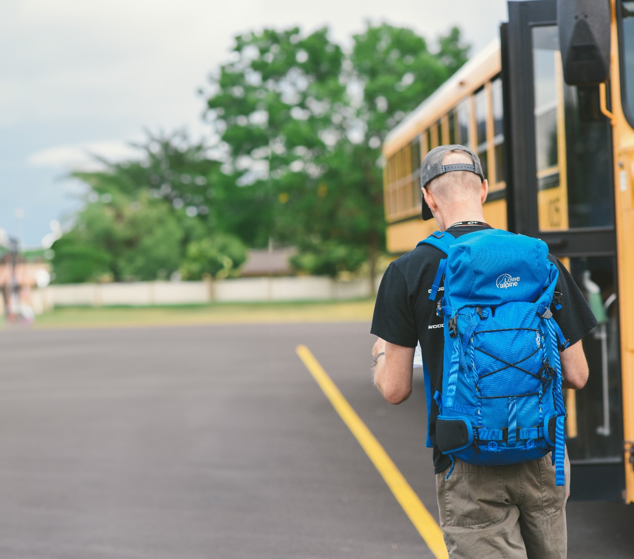 A student wearing a backpack about to board a bus.