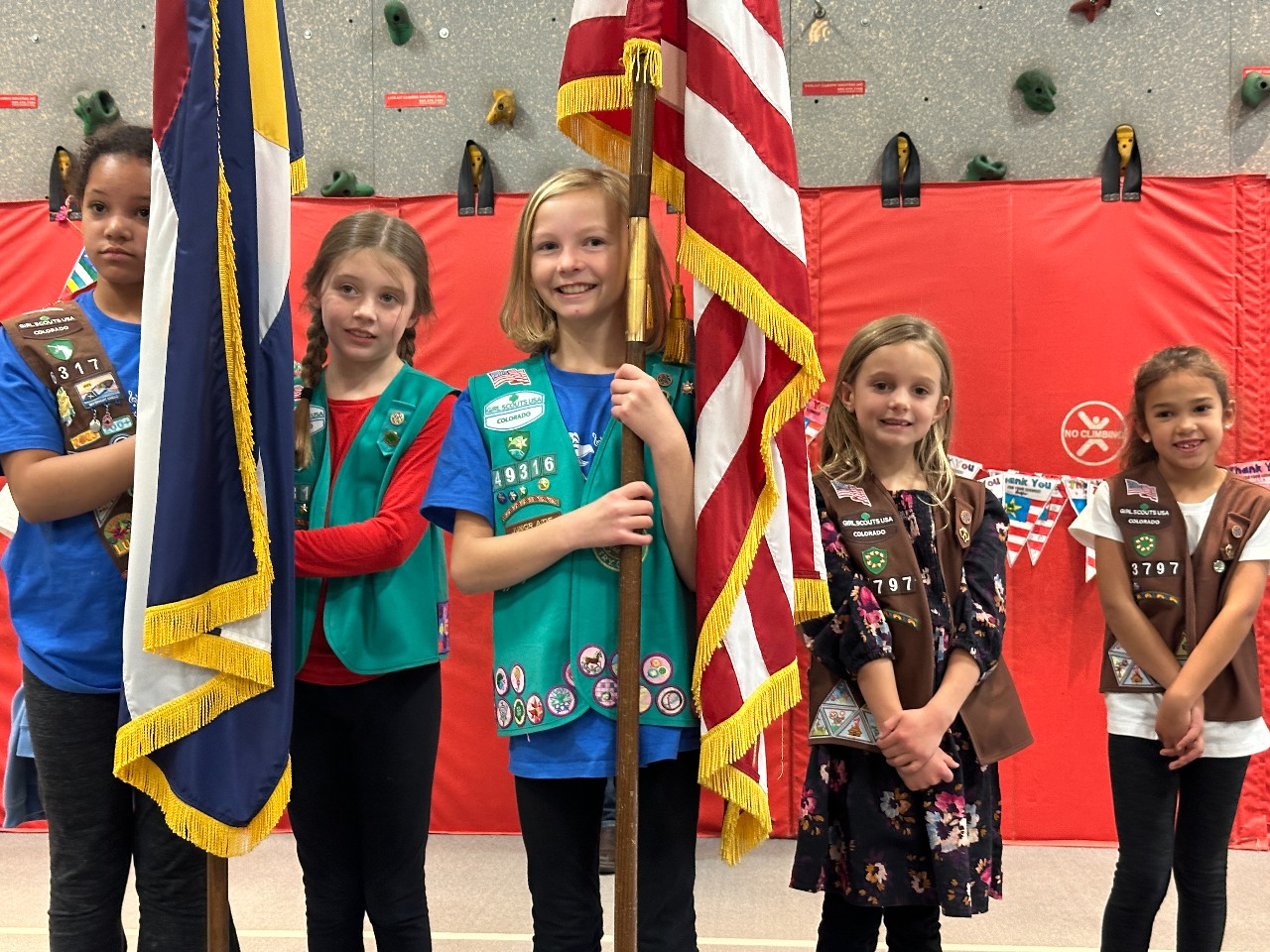 EES students in their Girl Scout uniforms stand with the U.S. and CO flags.