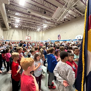 Students and parents stand for the Pledge of Allegiance during the Veterans Day assembly.