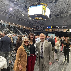 Three people smile for a picture in an arena